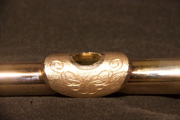 Close-up of ornate engraving design on gold-plated lip plate