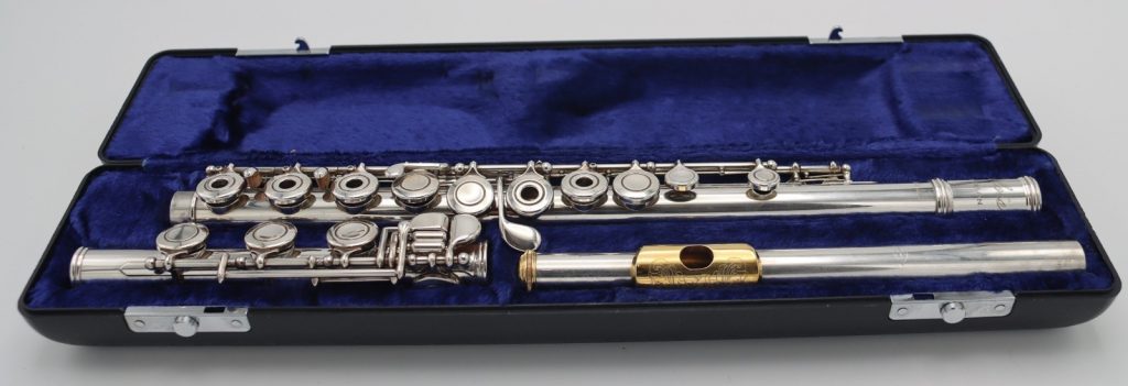 Emmerson Soloist flute displayed in an open blue velvet-lined case, showing full body, keys, and gold lip plate headjoint